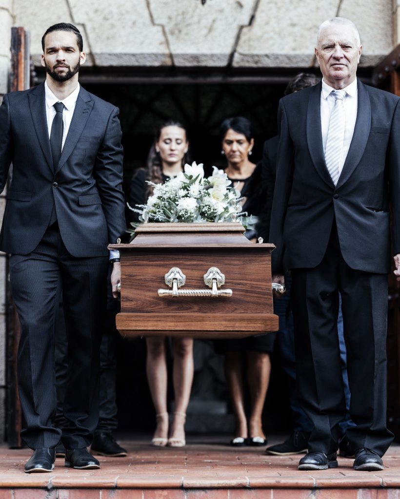 Funeral, church and pallbearers with a coffin, family and mourning people in emotional distress. Ch